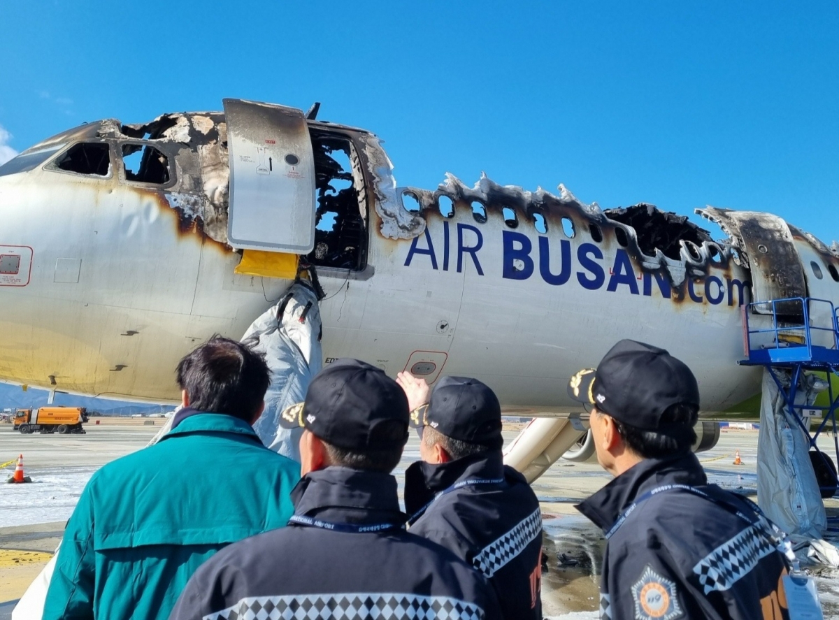 A fire-damaged Air Busan aircraft with investigators nearby